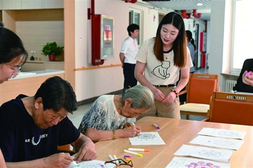 8月20日,郑金玉站着帮助养老院的老人们画画 新华社发